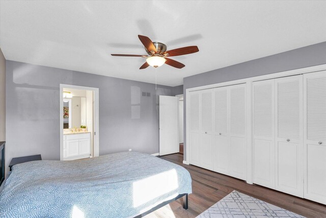 bedroom with ensuite bathroom, sink, multiple closets, dark hardwood / wood-style flooring, and ceiling fan