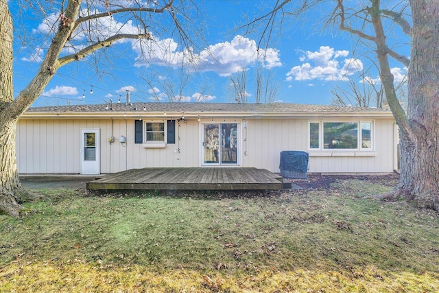 rear view of house with a wooden deck and a lawn