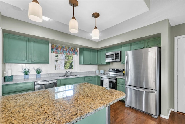 kitchen featuring stainless steel appliances, sink, decorative light fixtures, and green cabinetry