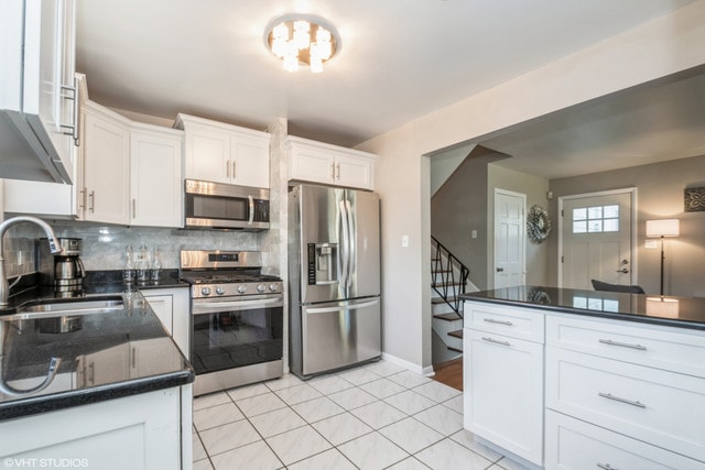 kitchen with sink, decorative backsplash, white cabinets, and appliances with stainless steel finishes