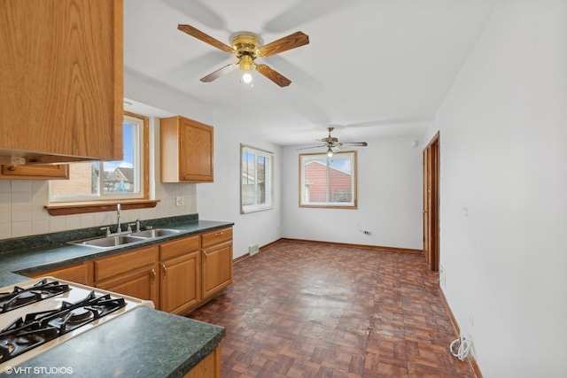 kitchen featuring dark parquet floors, stovetop, sink, decorative backsplash, and ceiling fan