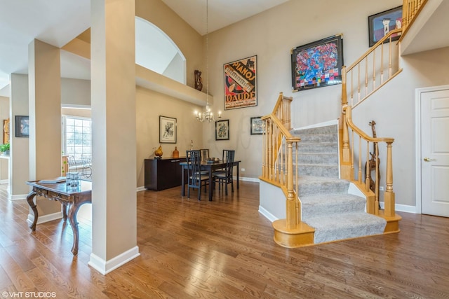 stairway featuring hardwood / wood-style flooring, a chandelier, and a towering ceiling