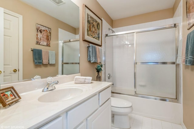 full bathroom with bath / shower combo with glass door, vanity, tile patterned floors, and toilet