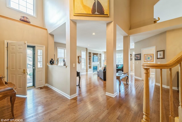 foyer featuring a towering ceiling, plenty of natural light, and hardwood / wood-style floors