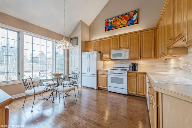 kitchen featuring sink, white appliances, hardwood / wood-style flooring, hanging light fixtures, and decorative backsplash