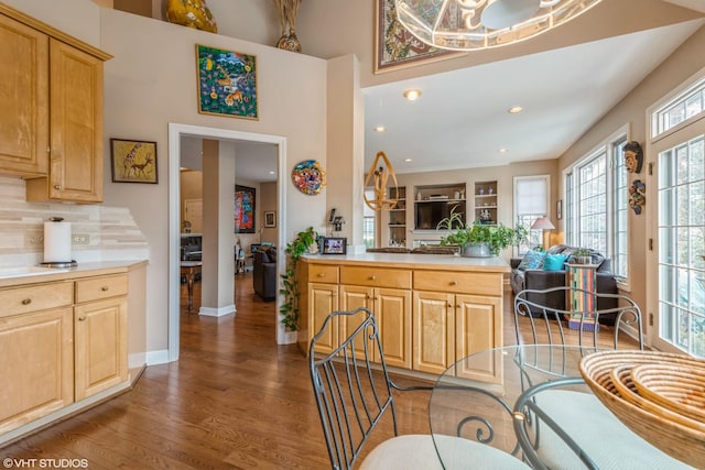 kitchen with dark hardwood / wood-style floors, kitchen peninsula, decorative backsplash, and light brown cabinets