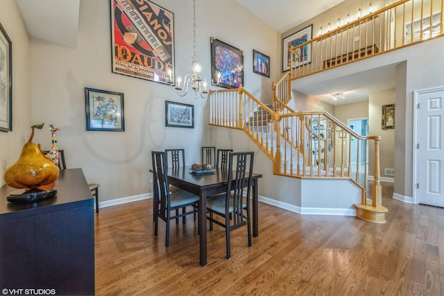 dining space with a high ceiling, wood-type flooring, and an inviting chandelier