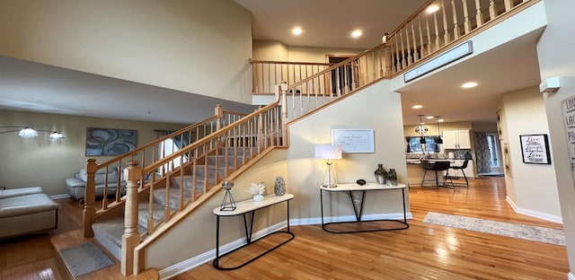 stairs with hardwood / wood-style flooring and a towering ceiling