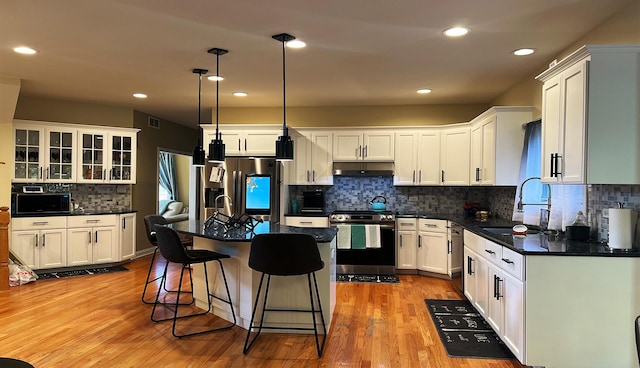 kitchen with sink, white cabinetry, a kitchen island, pendant lighting, and stainless steel appliances