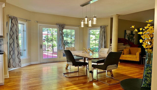 dining space featuring decorative columns, plenty of natural light, and light wood-type flooring