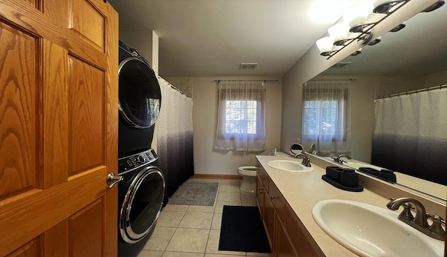 bathroom with tile patterned flooring, vanity, stacked washer / drying machine, and toilet