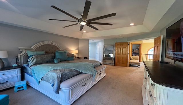 carpeted bedroom with a raised ceiling and ceiling fan