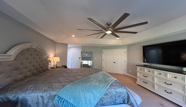 carpeted bedroom featuring ceiling fan and a raised ceiling