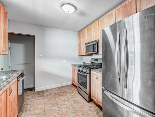 kitchen featuring light brown cabinetry, light stone countertops, and stainless steel appliances