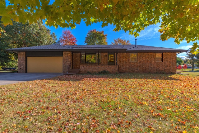 ranch-style house featuring a garage, a front lawn, aphalt driveway, and brick siding