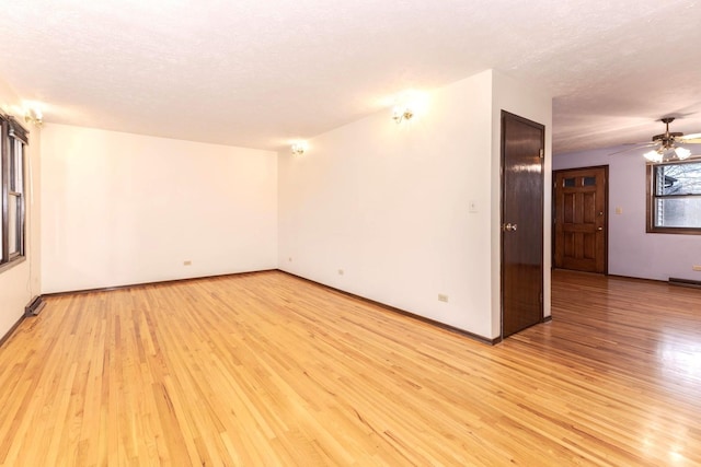 spare room featuring ceiling fan, light hardwood / wood-style flooring, and a textured ceiling