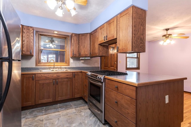 kitchen with appliances with stainless steel finishes, sink, ceiling fan, and kitchen peninsula