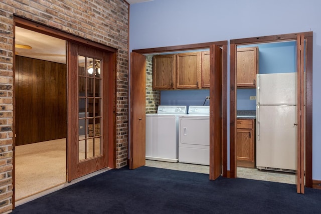 washroom featuring cabinets, brick wall, carpet, and washer and clothes dryer