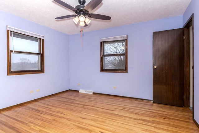 unfurnished room featuring ceiling fan, light hardwood / wood-style floors, and a textured ceiling