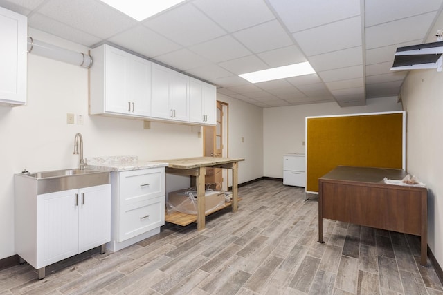 kitchen featuring white cabinetry, a paneled ceiling, sink, and light wood-type flooring