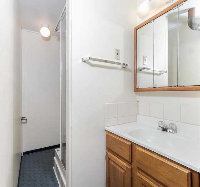 bathroom with vanity, tasteful backsplash, and a shower with shower door