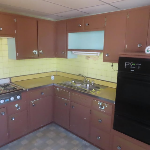 kitchen with cooktop, sink, oven, and backsplash