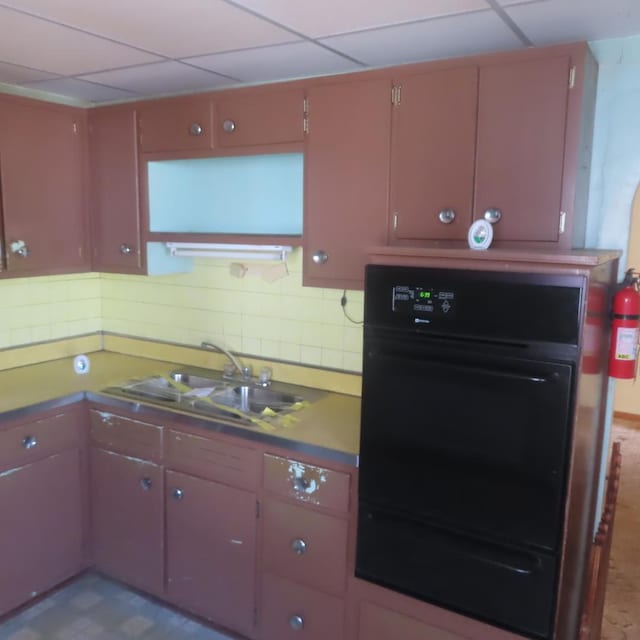 kitchen with tasteful backsplash, sink, a paneled ceiling, and oven