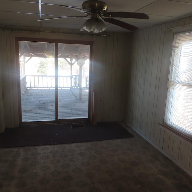 unfurnished room with ceiling fan and wooden walls