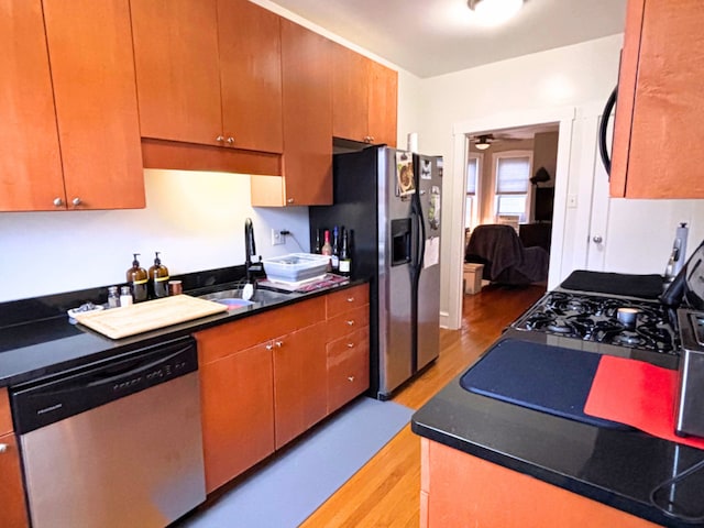 kitchen with stainless steel appliances, sink, and light hardwood / wood-style flooring