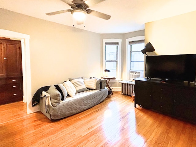 living room with radiator heating unit, ceiling fan, and light hardwood / wood-style flooring