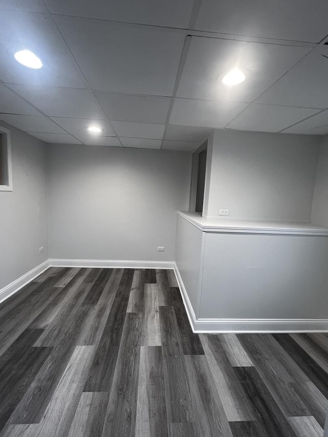 basement with dark wood-type flooring and a paneled ceiling