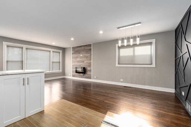 unfurnished living room featuring dark hardwood / wood-style floors and a tiled fireplace