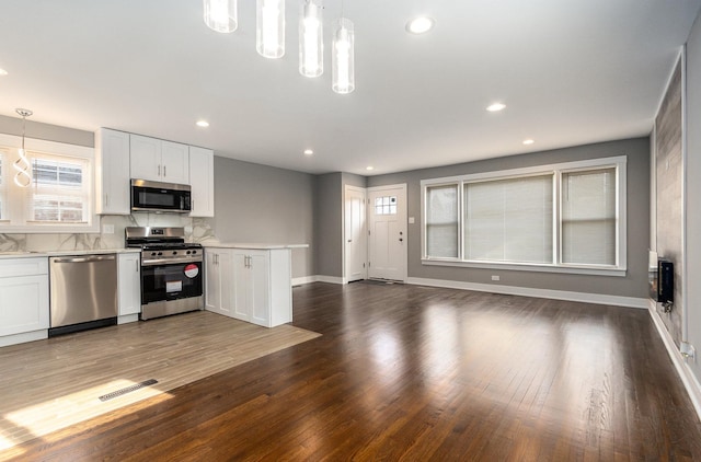 kitchen with appliances with stainless steel finishes, decorative light fixtures, and white cabinets