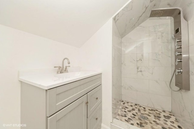 bathroom with tiled shower, lofted ceiling, and vanity