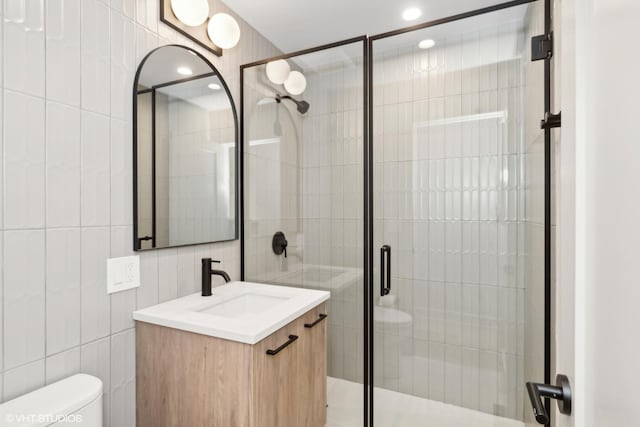 bathroom featuring tile walls, vanity, a shower with door, and toilet