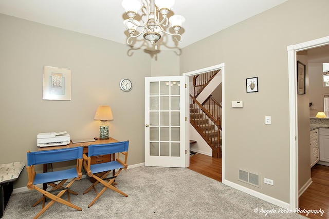 carpeted home office featuring an inviting chandelier