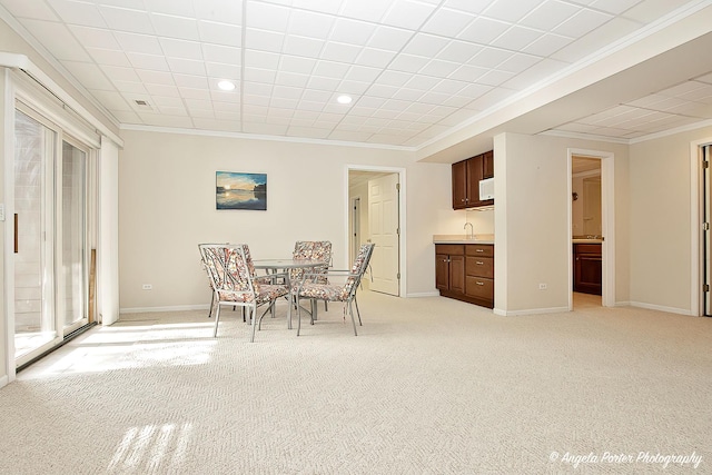 dining space with crown molding and light colored carpet