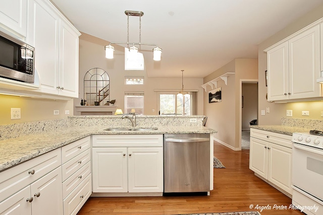 kitchen featuring stainless steel appliances, sink, kitchen peninsula, and decorative light fixtures