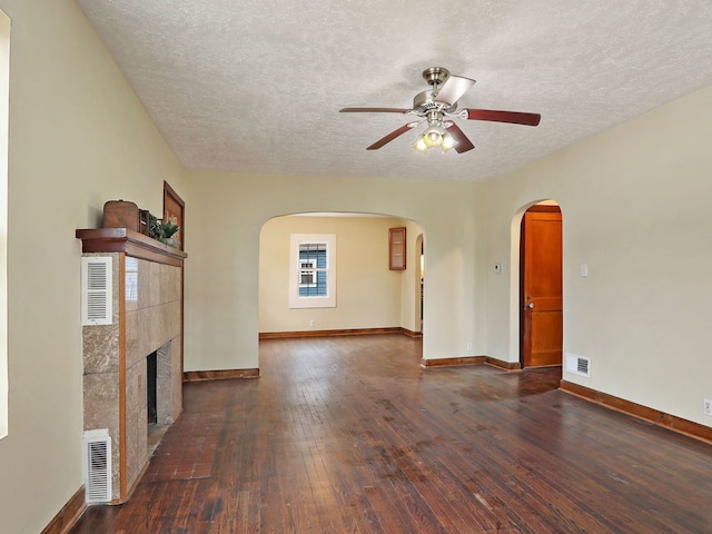 unfurnished living room with ceiling fan, dark hardwood / wood-style floors, a textured ceiling, and a fireplace