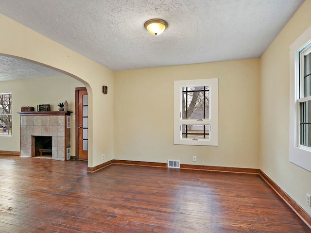 unfurnished living room featuring dark wood-type flooring, a fireplace, and a textured ceiling