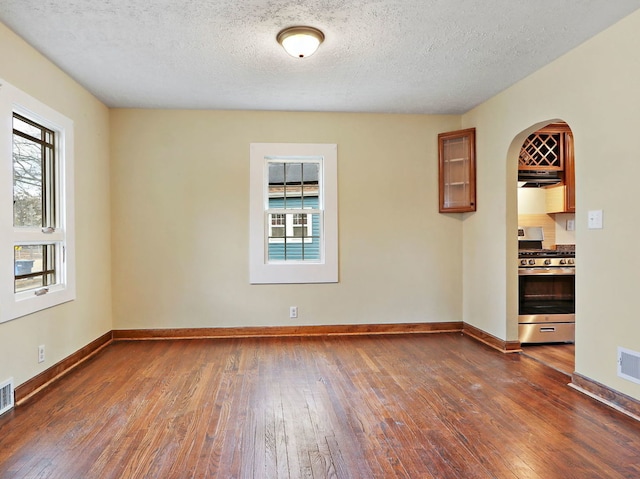 unfurnished room featuring dark wood-type flooring and a textured ceiling