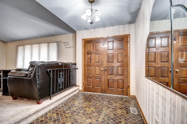 foyer featuring baseboards, lofted ceiling, and a notable chandelier