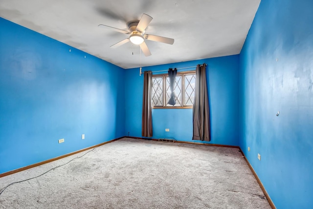 carpeted spare room featuring baseboards and a ceiling fan