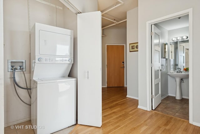 laundry area featuring light hardwood / wood-style flooring and stacked washing maching and dryer