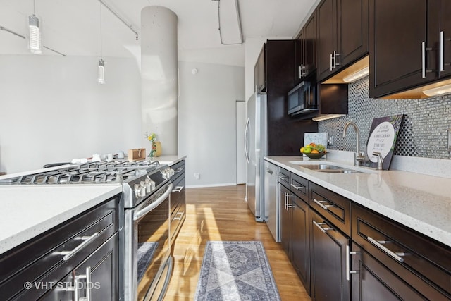 kitchen featuring sink, light hardwood / wood-style flooring, stainless steel appliances, decorative backsplash, and decorative light fixtures