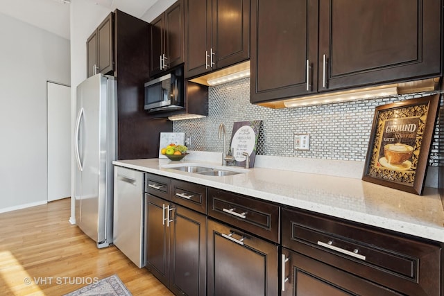 kitchen with sink, light stone counters, tasteful backsplash, light hardwood / wood-style flooring, and appliances with stainless steel finishes