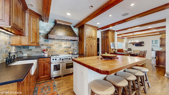 kitchen featuring double oven range, a center island, sink, and custom range hood