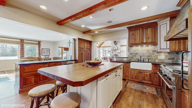 kitchen with high end range, backsplash, a center island, kitchen peninsula, and beamed ceiling