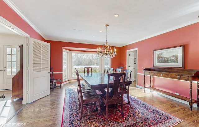 dining space with an inviting chandelier, ornamental molding, french doors, and light wood-type flooring