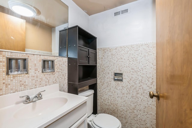 bathroom with vanity, toilet, and tile walls